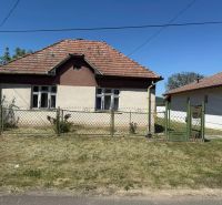 A family house in Hont has a sloped roof and is enclosed by a metal fence.