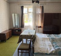 A room in a family house with 1960s furniture, wallpaper, and a green carpet.