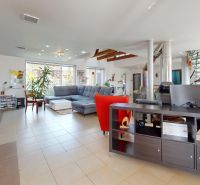 Living room with a corner sofa, open space, and spiral staircase in a family house.