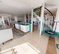 Interior of a family house with a modern kitchen unit, spiral staircase, and green tiles.