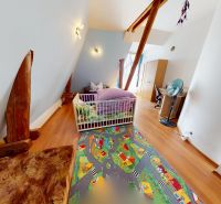 A children's room in a family house with a wooden decor floor and a colorful carpet.