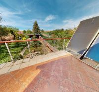 The terrace of a family house in Veľké Chlievany with a view of the garden and solar panels.