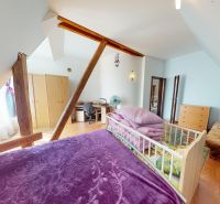 Attic bedroom in a family house with a wooden decor floor and a wooden beam.