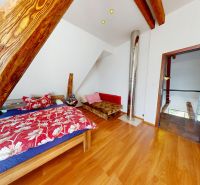 Attic room in a family house with a bed, decorative wood, and a floor with a wooden decor.