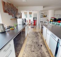 A kitchen in a family house with black countertops and decorative art on the wall.