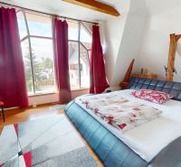 A bedroom in a family house with large windows and a wooden decor floor.