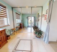 A hallway in a family house with flowers, light-colored walls, and mirrored doors.