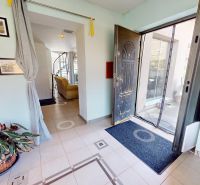 Entrance hall with open doors, paintings, and a plant in a family house.