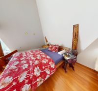 Attic bedroom in a family house with floral bedding and wood-patterned flooring.