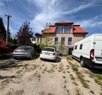 A family house in Veľké Chlievany with three parked cars on a gravel property.