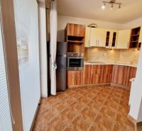A kitchen with a kitchen unit and a wooden decor floor in a 3-room apartment.