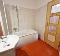 A bathroom with light tiles and red flooring in a 3-room apartment.