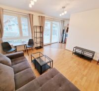 A bright living room with a sofa, a table, and a wooden decor floor in a 3-room apartment.