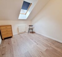 A room in a 3-room apartment with a wooden decor floor, a chest of drawers, and a chair.