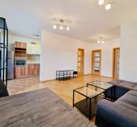 Living room in a three-room apartment with a gray sofa and a wooden-patterned floor.