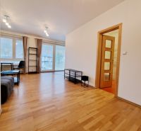 Living room with wood-patterned flooring in a three-room apartment.