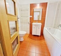 A bathroom in a 3-room apartment with a bathtub, sink, and orange tiles.