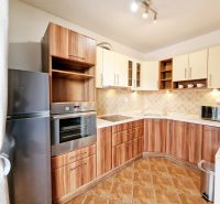 A kitchen in a 3-room apartment with a wooden decor floor and a corner kitchen unit.