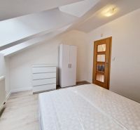 Attic bedroom in a 3-room apartment with white furniture and a wooden decor floor.