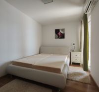 Bright bedroom in a family house with a bed and wooden decor flooring.