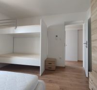 Bedroom with a bunk bed, wooden decor flooring, and storage space in a family house.