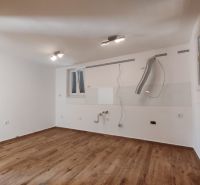 An empty kitchen in a family house with a wood-patterned floor.