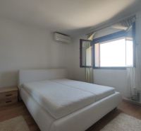 Bedroom in a family house with a large window and a bed, floor with wooden decor.
