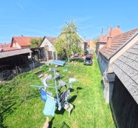 The garden of a family house in the village of Svinná with a car, a shelter, and a clothesline.