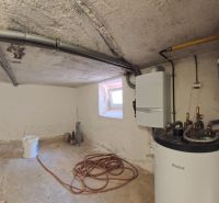 A technical room with a boiler in a family house, simple equipment, pipes, window, tools.