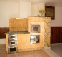 Tiled stove in a family house with ceramic cladding and wood decor on the walls.