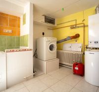 Boiler room in a family house with a washing machine, dryer, and boiler, light tiles.