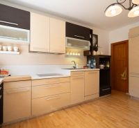 A kitchen in a family house with a wooden decor floor and light-colored furniture.