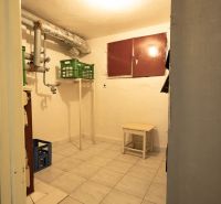 A practical basement in a family house with a tiled floor, small furniture, and piping.