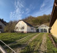 A family house in Štós surrounded by greenery and a wooden structure of a shelter.