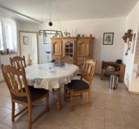 A kitchen in a family house with a round table, wooden chairs, and a sideboard.