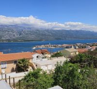 View of the coast and a family house in the town of Vinjerac with mountains in the background.