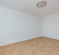 An empty room with white walls and a wooden decor floor in a 3-room apartment.