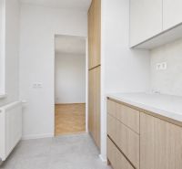 A kitchen with cabinets and a view of the floor with a wooden decor in a 3-room apartment.