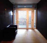 A dark space with a sofa, glass doors, and tiles, ideal for commercial premises.