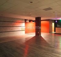 A large room with wooden flooring and colorful lighting, suitable for commercial spaces.