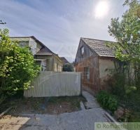 A family house in Orešany with two buildings, surrounded by lush greenery and a wooden fence.
