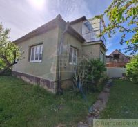 A family house in Orešany with a green exterior and a garden, surrounded by trees.