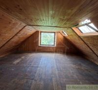 An attic with wooden paneling and a large window in a family house.