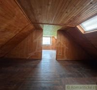 An attic with wooden paneling and windows in a family house.