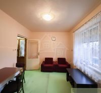 Living room with red seating, table, and curtains, Family house.