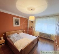 A bedroom in a family house with wooden decor, a bed, and furniture in warm colors.