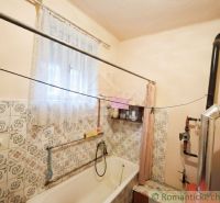 Bathroom with a bathtub in a family house, tiles with a floral pattern and a curtain.