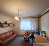 A room in a family house with a brown sofa, a desk, and a colorful armchair.