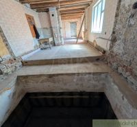 The interior of a family house under renovation with exposed walls and a staircase.