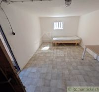 A room in a family house with a bed, a table, and a window, light-colored walls.